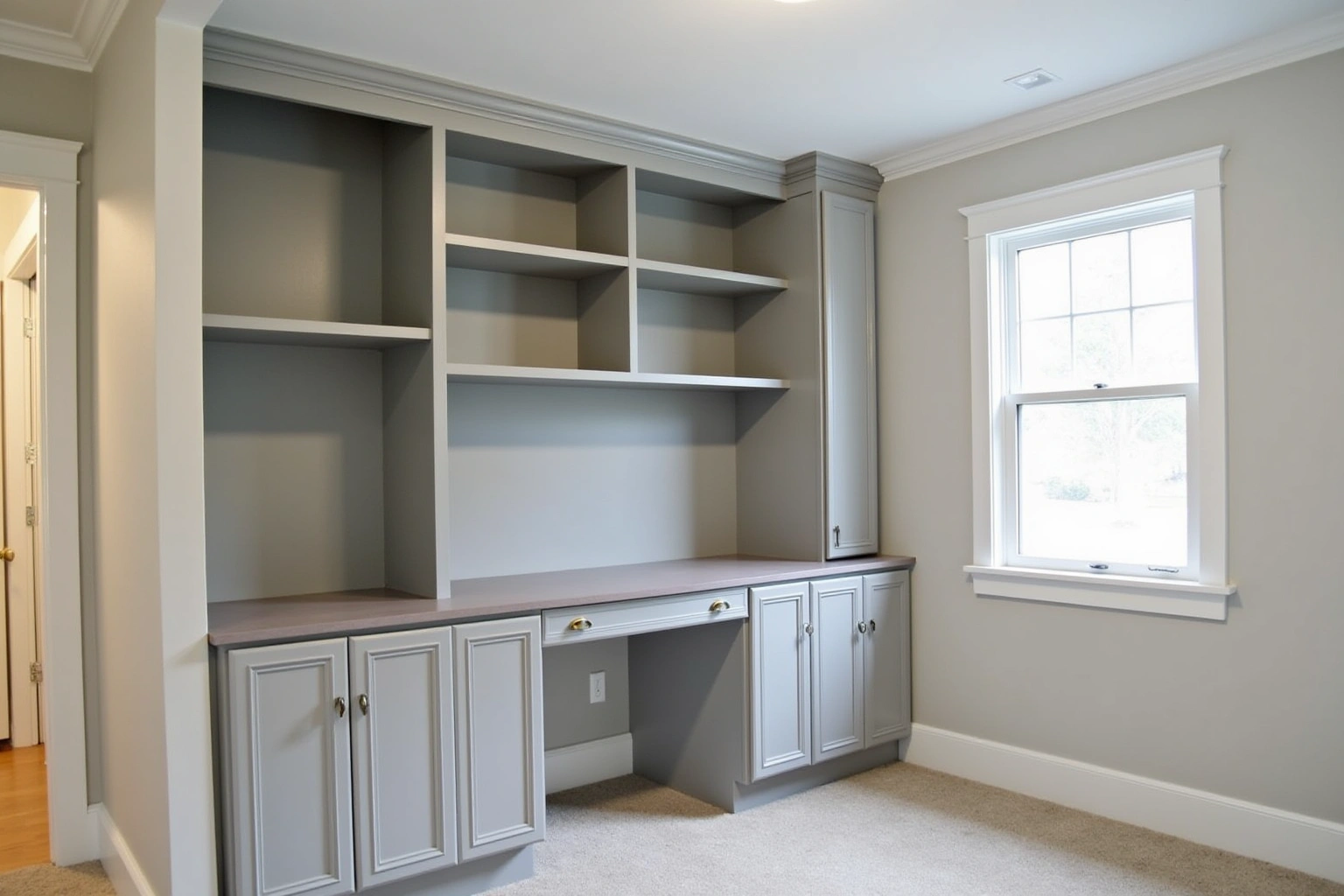 Grey painted built-in wall with open shelves over a built-in desk and base cabinets, window at the side.